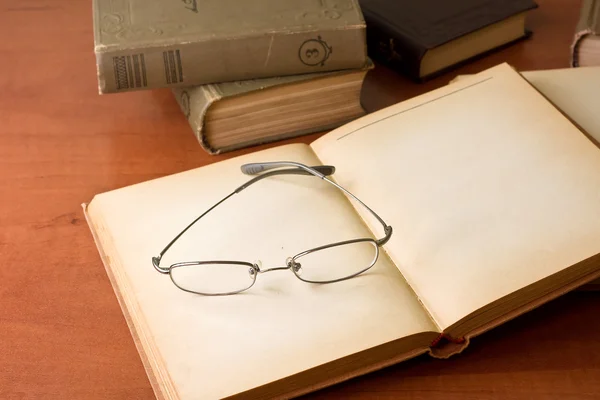 Куча старых книг с очками для чтения — стоковое фото