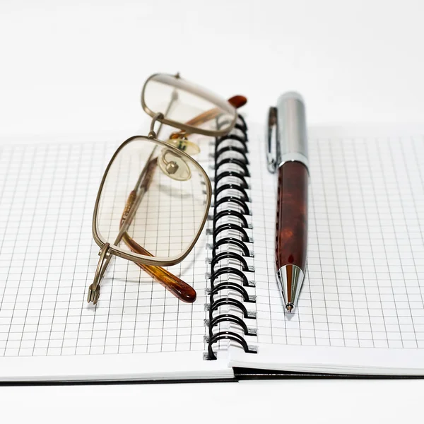 Glasögon på en anteckningsbok och penna — Stockfoto