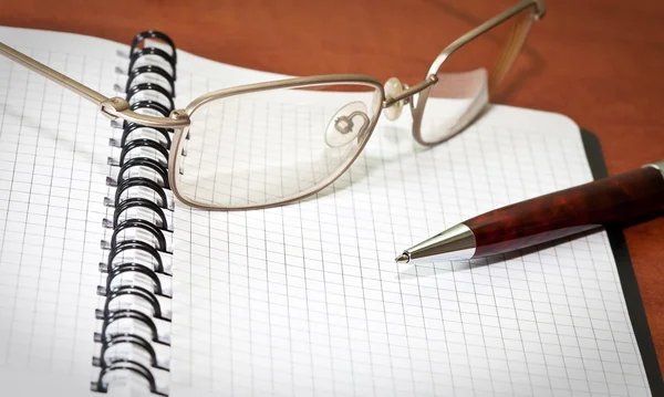 Glasögon, anteckningsbok och penna — Stockfoto