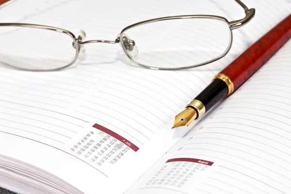 Planificador diario con gafas y bolígrafo — Foto de Stock