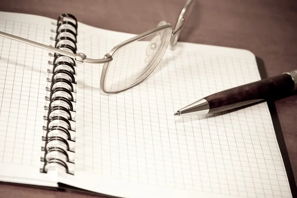 Ручка и очки на блокноте — стоковое фото