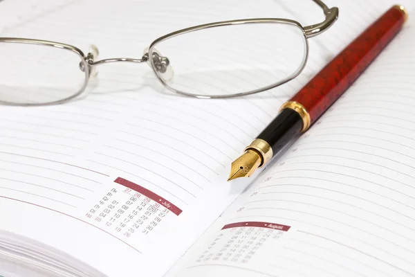 Pen and eyeglasses on agenda page — Stock Photo, Image
