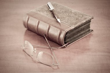 Old book with reading glasses and pen clipart