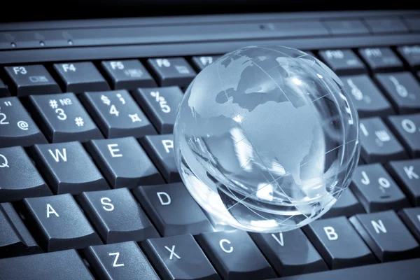 Glas globe på en laptop tangentbord — Stockfoto