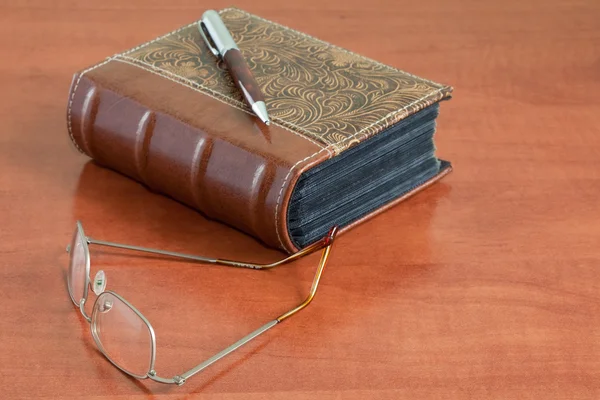 Knihovna desk se stará kniha, brýle a pen — Stock fotografie