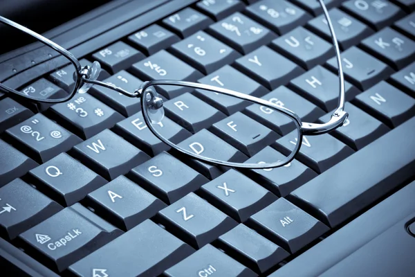 Glasses over laptop keyboard — Stock Photo, Image