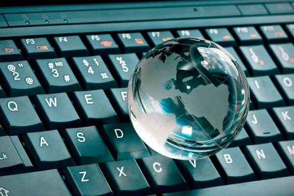 Маленький стеклянный глобус на клавиатуре ноутбука — стоковое фото