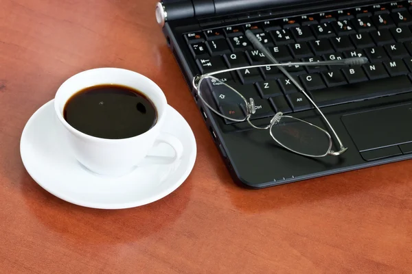Taza de café con un ordenador portátil y vasos — Foto de Stock
