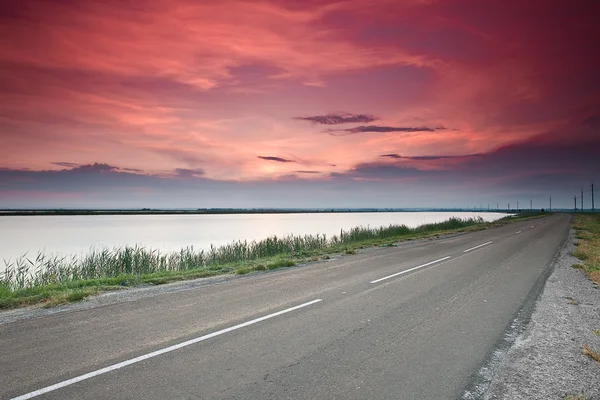 Vägen under dramatiska röd solnedgång himmel — Stockfoto