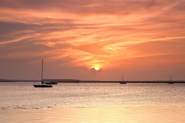 航行ボートのシルエットと赤い海に沈む夕日 — ストック写真