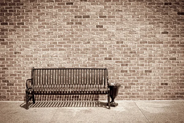 Metal bench against a brick wall — Stock Photo, Image