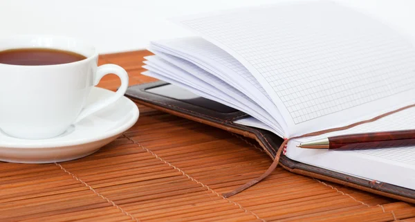 Witte kopje thee met notebook en pen — Stockfoto