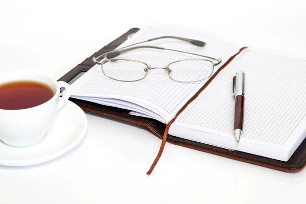 Notebook z pióra, szklanki i filiżanki herbaty — Zdjęcie stockowe