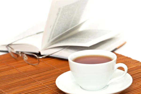 Chávena branca de chá e livro com óculos — Fotografia de Stock