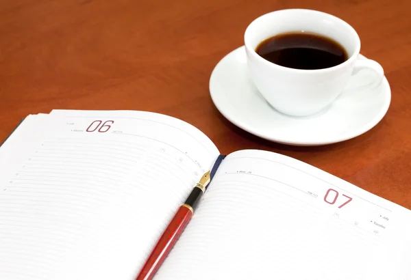 Кофейная чашка, ноутбук и ручка — стоковое фото