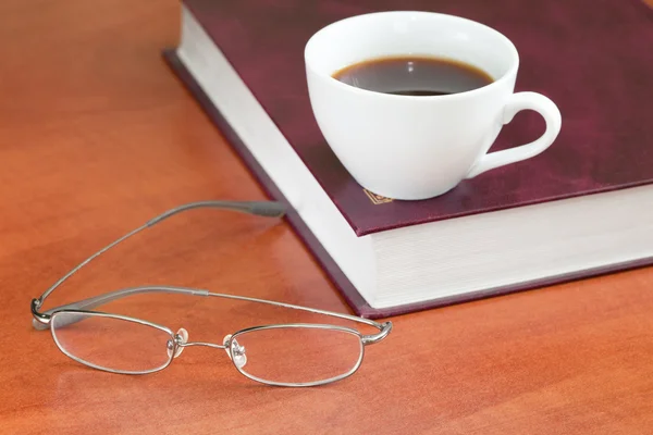 Kopp kaffe med bok och glasögon — Stockfoto