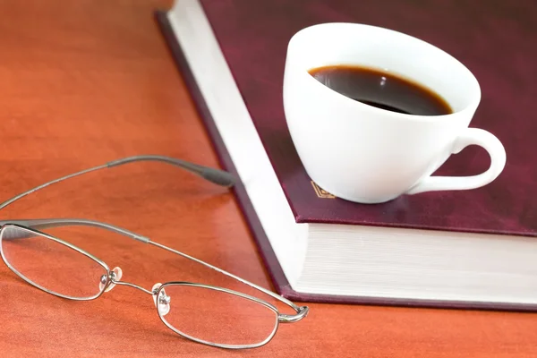 stock image Cup of coffee with book and glasses