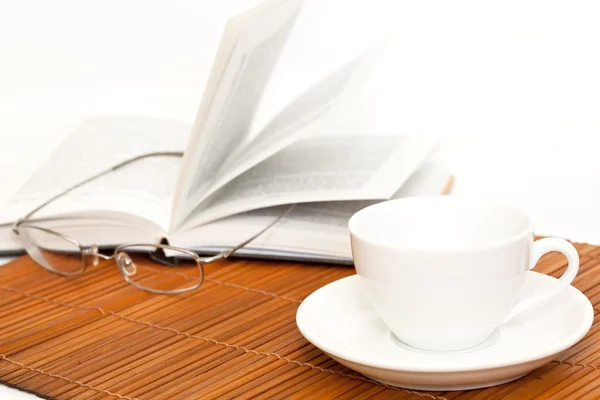 Xícara branca de café e livro com óculos — Fotografia de Stock