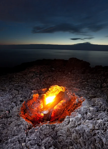 Small campfire on rocky coast at night — Zdjęcie stockowe