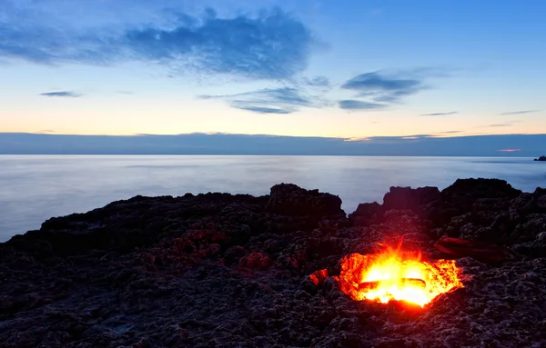 stock image Small campfire on rocky coast at night