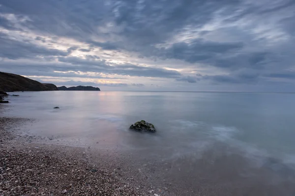 stock image Cloudy sunrise on rocky seashore