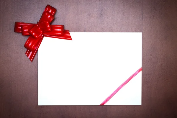 Arco vermelho com cartão de papel — Fotografia de Stock