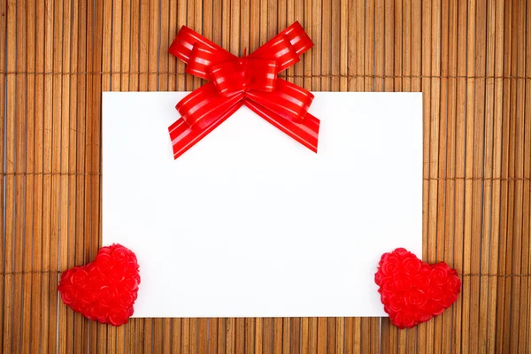 Iki kırmızı Kalpler ve yay ile kağıt kartı — Stok fotoğraf