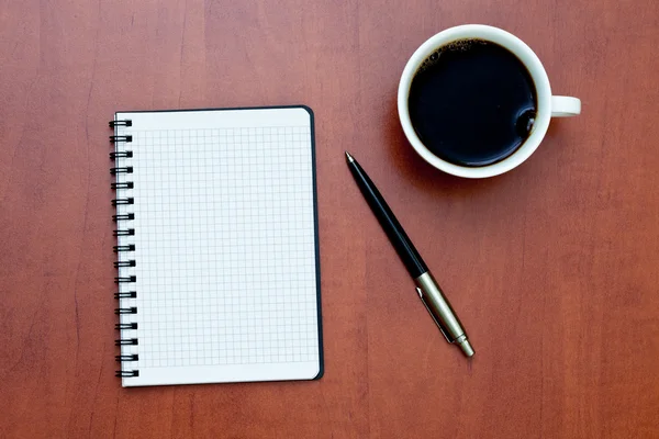Ручка на белой спирали ноутбука с чашкой кофе — стоковое фото