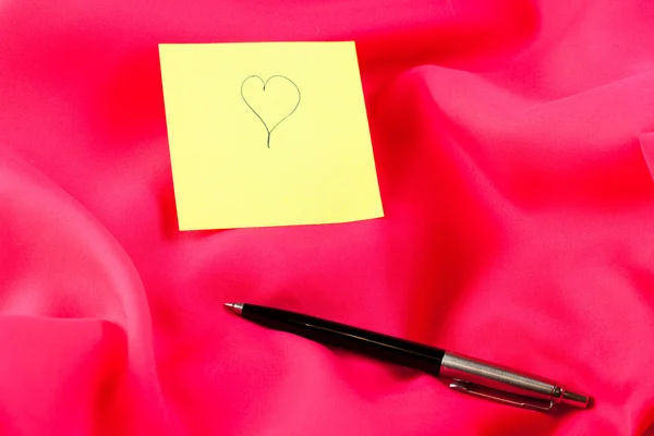 Nota de papel amarillo con la palabra "amor", corazón y pluma —  Fotos de Stock