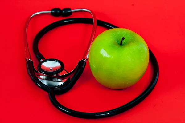 Zelené jablko s stetoskop — Stock fotografie