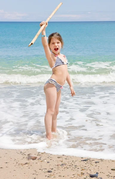 Girl with a stick in his hand on the beach — Stock Photo, Image
