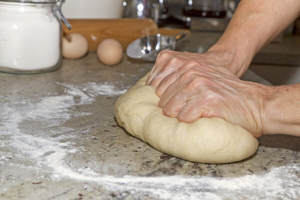 Female hands kneading dough on a table