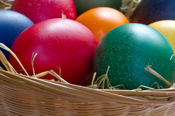 Ovos de páscoa coloridos em uma pequena cesta — Fotografia de Stock