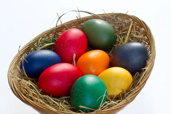 Цветные пасхальные яйца в маленькой корзине — стоковое фото