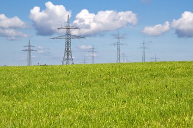 Electrical towers on a meadow in spring time clipart