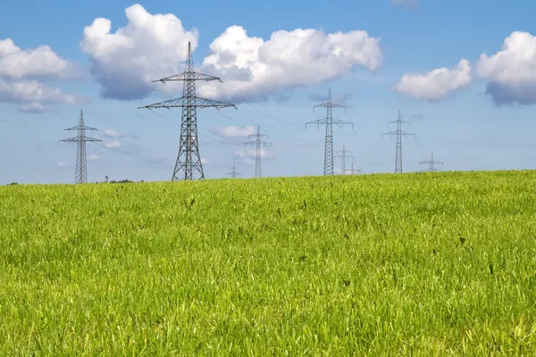 Torres elétricas em um prado em tempo de primavera — Fotografia de Stock