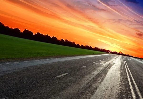Estrada turva vazia sob a luz do pôr do sol com nuvens — Fotografia de Stock