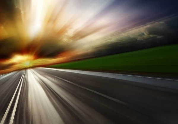 Camino borroso vacío bajo la luz del atardecer con nubes — Foto de Stock