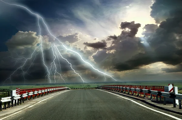 Асфальтовая дорога с забором против голубого неба — стоковое фото