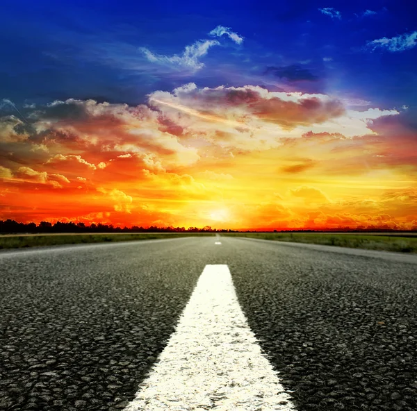 Road vanishing to the horizon under sun rays coming down trough the dramatic stormy clouds — Stock Photo, Image