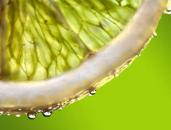 stock image Drops of juice falling of the succulent lemon. A strong light behind the lemon gives the dark aspect.