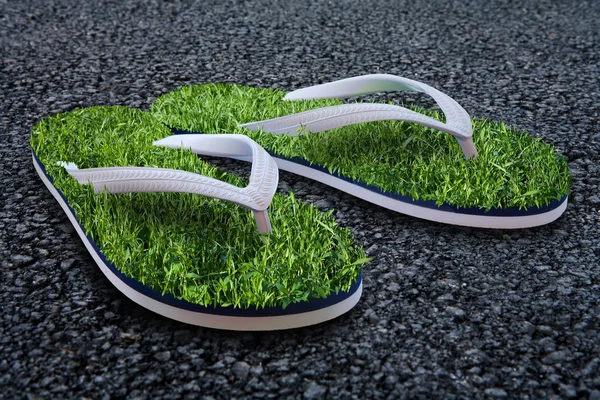 Beach slippers with a grass on city asphalt — Stock Photo, Image