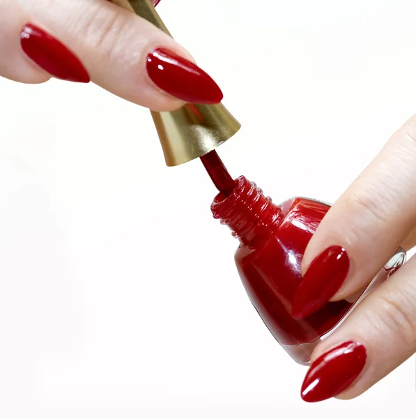 Las manos femeninas con la botella del barniz rojo — Foto de Stock