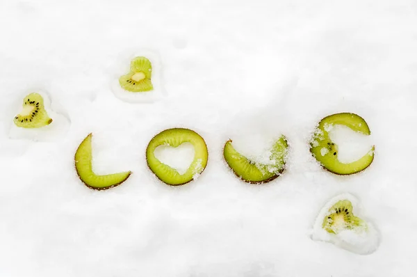 Heart shaped into a slice of kiwi fruit, staying on snow — Stock Photo, Image