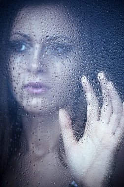 A girl watching through the window after a rain. Portrait. clipart