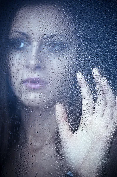 Ένα κορίτσι βλέποντας μέσα από το παράθυρο μετά από μια βροχή. πορτρέτο. — Φωτογραφία Αρχείου
