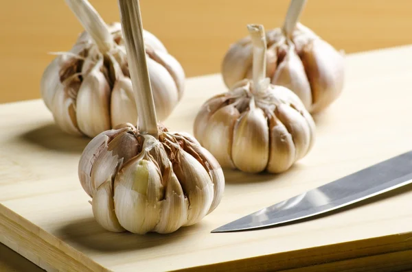 Garlic and knife on cutting board — Stock Photo, Image