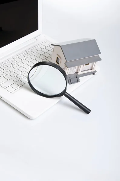 Magnifying glass, model house and laptop — Stock Photo, Image