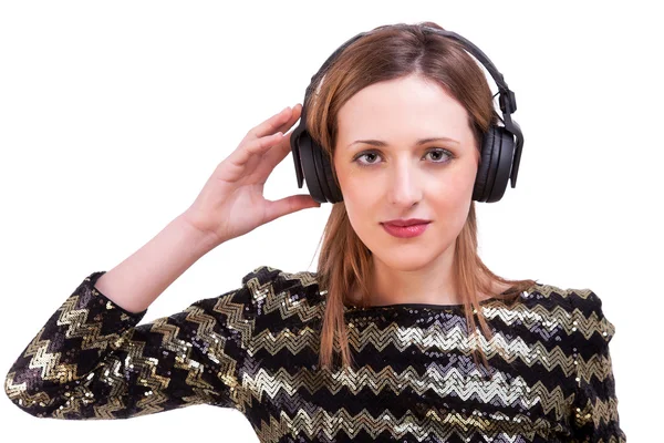 Beautiful woman standing listening to music on black headphones, isolated on white, studio shot — Stock Photo, Image