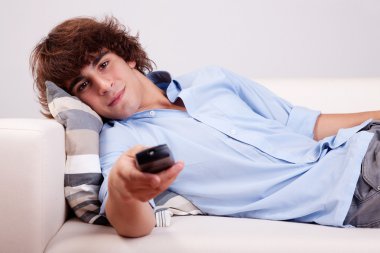 Young man, watching television with the command at hand clipart